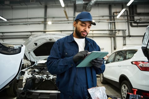 Young mechanic reviews car maintenance tasks at repair service center