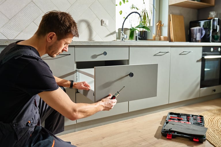 Handyman assembling kitchen drawer with screwdriver